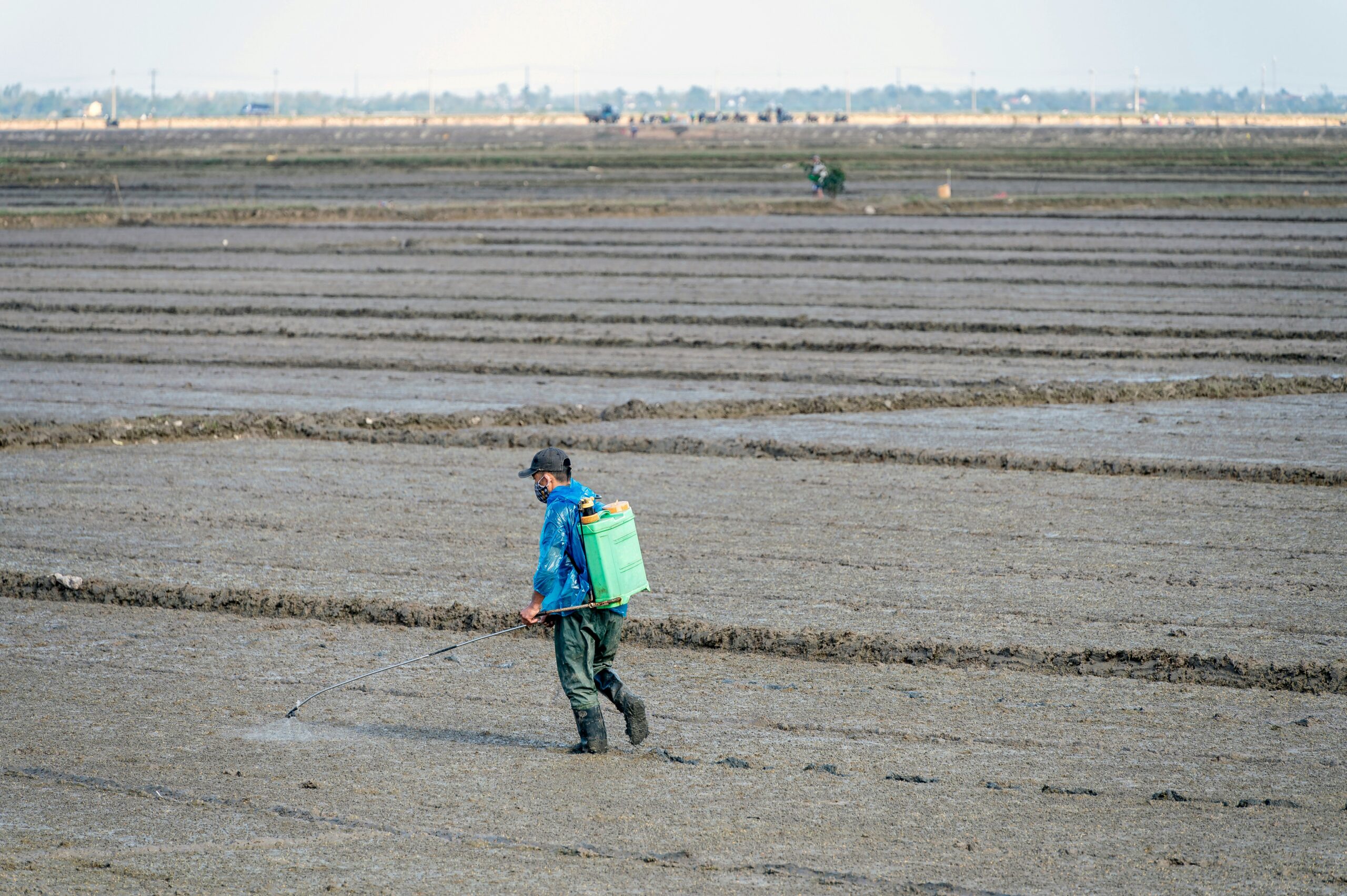 a man walking across a field carrying a green bag